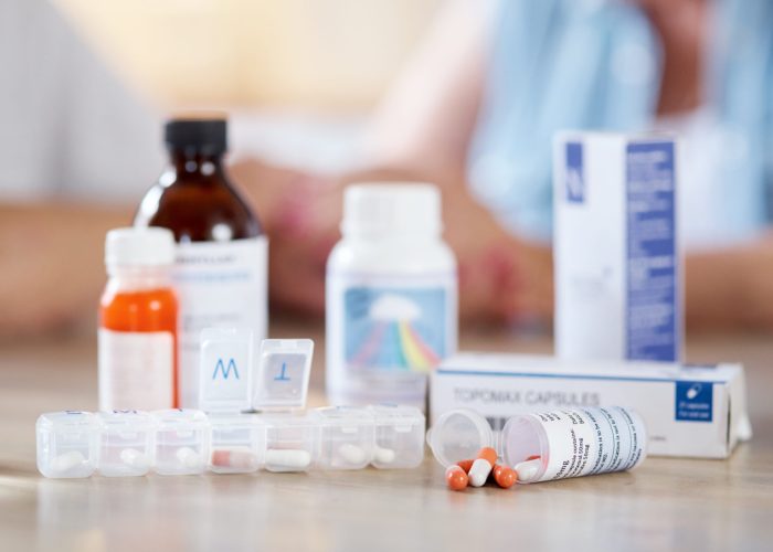 Cropped shot of medication on a kitchen table with an unrecognizable couple in the background.