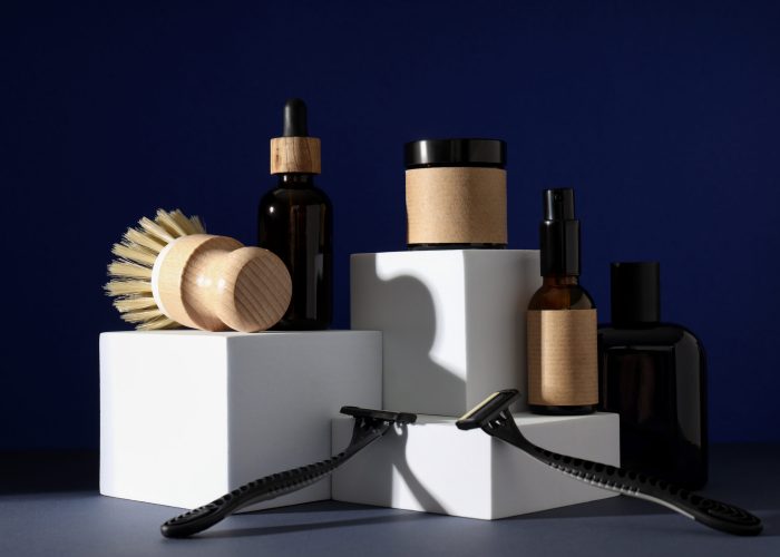 Shaving tools and bottles of men's cosmetics on dark blue background